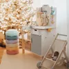 A child's wooden workbench and accessories are set up in a room with a decorated Christmas tree in the background. Produktbild-Vorschau