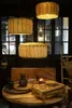 A dining table setting with a wooden cutting board with a drawer, a pitcher, and other tableware, under woven pendant lights. Náhľad obrázku produktu
