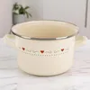 A cream-colored enamel pot with red heart decorations sits on a marble countertop. Anteprima dell’immagine prodotto