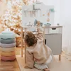 A child is playing with a wooden toy workbench in a room decorated with a Christmas tree. Produktbild-Vorschau