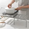 A person is using a portable induction cooktop on a shelf organizer in a kitchen setting. Podgląd zdjęcia produktu