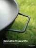 Close-up of a black metal fire pit with a handle, set against a blurred green grassy background. Produktbild-Vorschau