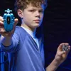 A young boy is holding two Beyblade accessories, a launcher and a beyblade part, in front of a dark background. Anteprima dell’immagine prodotto