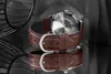 A close-up of a watch with a brown leather strap, reflected on a dark surface. Produktbild-Vorschau