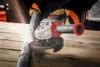 A person wearing work gloves is using an angle grinder to cut a metal pipe on a wooden surface. Sparks are flying from the cutting action. Náhľad obrázku produktu