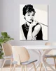 A diamond painting of Audrey Hepburn is displayed on a wall above a dining table with chairs. Produktbild-Vorschau
