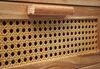 A close-up view of a wooden drawer with a cane weave panel and a wooden handle. Podgląd zdjęcia produktu