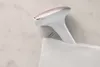 A white and rose gold IPL hair removal device is partially inserted into a white pouch. Náhľad obrázku produktu