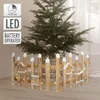 A small artificial Christmas tree surrounded by a decorative wooden fence with LED lights. Náhled obrázku produktu