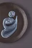 A swatch of silver-grey cream is swirled on a dark, textured plate. Podgląd zdjęcia produktu