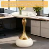 A round side table with a gold base and white top, placed in an office setting next to a desk. Produktbild-Vorschau