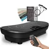 A black vibration plate with accessories and a remote control held by a hand. Produktbild-Vorschau