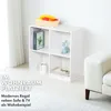 A white cube shelf unit with items on and in it, placed next to a white sofa in a room. Produktbild-Vorschau