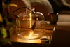 A decorative glass bottle with a filament light bulb inside, placed on a tray with a cup of coffee in the background. Produktbild-Vorschau