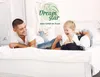 A family is lying on a bed, playing and smiling. Produktbild-Vorschau