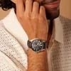 A man wearing a white knitted shirt is shown with his hand on his face, wearing a black leather strap watch on his wrist. Voir les images du produit