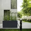 A modern outdoor setting with a concrete building, planters, and lush greenery. Anteprima dell’immagine prodotto