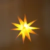 A lit-up, star-shaped lantern hangs from a string against a brown background. Voir les images du produit