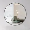 A round mirror reflecting a modern living room with a chair and lighting. Produktbild-Vorschau