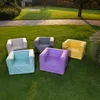 Five colorful lounge sofas are arranged on a green lawn in a backyard setting. Produktbild-Vorschau