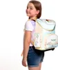 A young girl wearing a t-shirt and denim shorts is shown from the side, wearing a backpack. Produktbild-Vorschau
