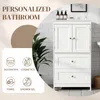 A white bathroom cabinet with two doors and two drawers, shown in a bathroom setting with decorative elements and icons representing different uses. Produktbild-Vorschau