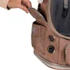 A close-up shot of a person's hand opening a pocket on a brown pet carrier bag. Náhľad obrázku produktu