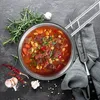 A top-down view of a pot of stew with ingredients and utensils arranged around it. Produktbild-Vorschau