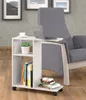 A white rolling side table with books and a plant is placed next to a gray armchair with a laptop on it. Podgląd zdjęcia produktu