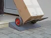 A person is using a hand truck with a box on it, going up a ramp placed over a doorstep. Produktbild-Vorschau