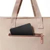 A close-up shot of a beige tote bag with a zippered pocket containing a black smartphone. Produktbild-Vorschau