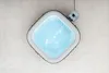 An overhead view of a square inflatable hot tub filled with blue water, placed on a tiled floor. Produktbild-Vorschau