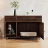 A dark wood sideboard with two drawers and two open compartments, one containing a cat statue and the other a shallow bowl, set against a light-colored wall. Náhled obrázku produktu