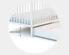A close-up view of the bottom of a white crib with a drawer pulled out, showing a measurement indicator. Voir les images du produit