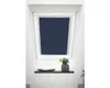 A dark blue roller blind is installed in a slanted window, with a small plant and a decorative bowl on a shelf below.
