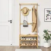 A wooden coat rack with shelves and hooks, holding clothes, a hat, and a bag, next to a white door and a potted plant. Náhled obrázku produktu