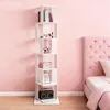 A white, multi-tiered, rotating bookshelf filled with books, makeup, and decorative items, placed against a pink wall next to a pink tufted headboard of a bed. Produktbild-Vorschau
