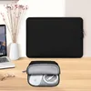 A black laptop sleeve and a small accessory pouch containing a white mouse and charging cable are displayed on a wooden desk next to a laptop and a vase of dried flowers. Náhľad obrázku produktu