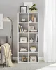 A white shelving unit filled with decorative items, books, and storage boxes, next to a sofa and a floor lamp. Produktbild-Vorschau