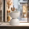 A stylish side table with decorative items on top, placed near a window with a view of a city street. Podgląd zdjęcia produktu