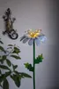 A decorative metal flower with LED lights and a metal gecko decoration on a wall. Produktbild-Vorschau