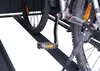 A close-up view of a bicycle's pedal and part of the frame, mounted on a dark metal rack. Náhled obrázku produktu