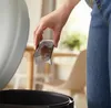A person is holding a lint remover over a trash can. Produktbild-Vorschau