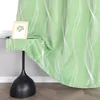 A close-up of a green curtain with a white wavy pattern, draped over a black table. A small framed picture is on the table. Produktbild-Vorschau