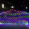 A net of colorful lights is draped over bushes and a fence at night. Voir les images du produit