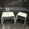 Two white shower stools are placed in a modern bathroom with black marble walls and floor. Produktbild-Vorschau