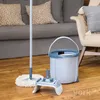A mop and bucket set is placed on a wooden floor in front of a sofa and chair. Podgląd zdjęcia produktu