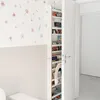 A children's room with a bookshelf filled with books and a decorative rainbow hanging on it. The wall is decorated with floral stickers. Podgląd zdjęcia produktu
