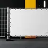 A white banner with blue grommets is attached to a metal fence. The banner is in the foreground, with a black and yellow background. Produktbild-Vorschau