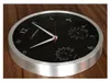 A round black wall clock with a silver frame sits on a wooden surface. Podgląd zdjęcia produktu